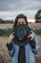 Portrait of young woman hiding behind black hat - VPIF00912