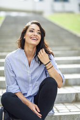 Portrait of laughing student sitting on stairs - JSMF00449