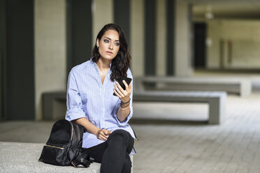 Porträt eines nachdenklichen Studenten mit Smartphone auf dem Campus - JSMF00457