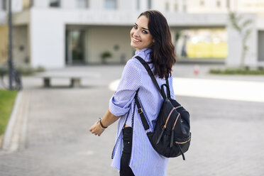 Porträt eines lächelnden Studenten mit Rucksack auf dem Campus - JSMF00464