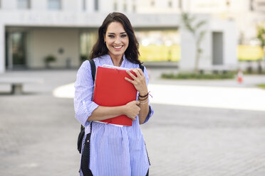 Portrait of happy student with notebooks on campus - JSMF00465