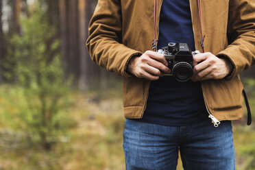 Finland, Lapland, close-up of man holding camera in rural landscape - KKAF02092