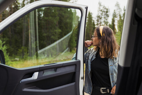 Finnland, Lappland, junge Frau an einem Auto in ländlicher Landschaft - KKAF02098