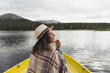 Finnland, Lappland, glückliche Frau mit Hut auf einem Boot auf einem See - KKAF02123