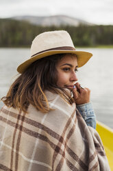 Finland, Lapland, woman wearing a hat on a boat on a lake - KKAF02124