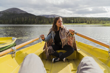 Finnland, Lappland, Frau mit Decke in einem Ruderboot auf einem See - KKAF02128