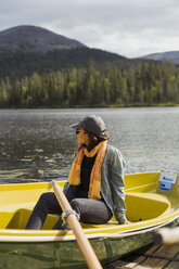 Finland, Lapland, woman sitting in a boat on a lake - KKAF02131