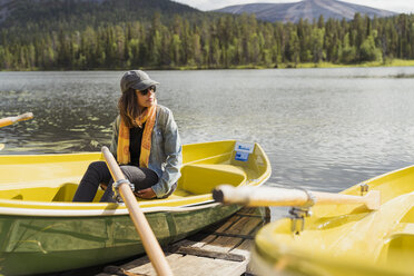 Finland, Lapland, woman sitting in a boat on a lake - KKAF02132