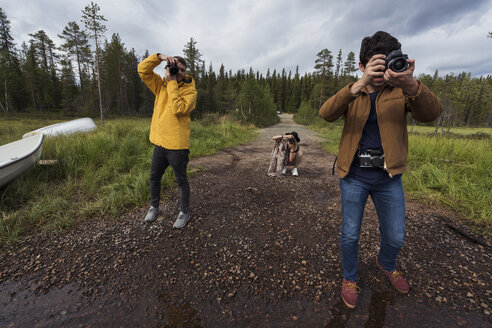 Finnland, Lappland, Fotografen beim Fotografieren in ländlicher Landschaft - KKAF02139