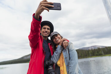 Finnland, Lappland, glückliches Paar macht ein Selfie an einem See - KKAF02149