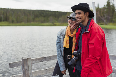 Finnland, Lappland, glückliches Paar steht auf einem Steg an einem See - KKAF02150