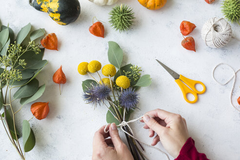 Autumnal decoration, ornamental pumpkins, woman's hand binding bunch of flowers - JUNF01327