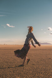 Side view of woman dancing at beach against blue sky during sunset - CAVF48987