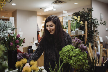 Blumenhändlerin arrangiert Blumen im Geschäft - CAVF49028