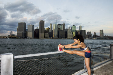 Weibliche Athletin trainiert am Fluss gegen den Himmel in der Stadt bei Sonnenuntergang - CAVF49072