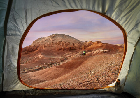 Mid distance view of hiker at desert seen through tent during sunset stock photo