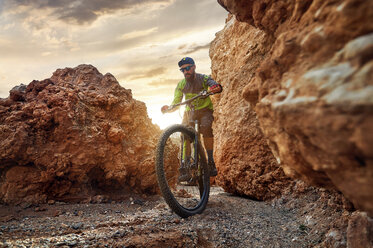 Wanderer Mountainbike durch Felsformationen in der Wüste bei Sonnenuntergang - CAVF49096