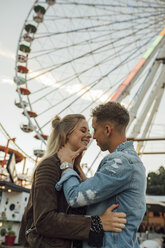 Young couple in love, kissing and embracing at a funfair - LHPF00094