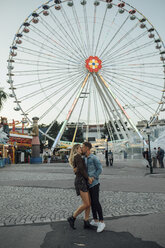 Junges verliebtes Paar, das sich auf einem Jahrmarkt küsst und umarmt - LHPF00096