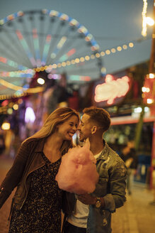 Romantisches Paar auf einem Jahrmarkt, das Zuckerwatte isst - LHPF00109