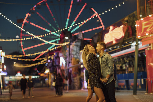 Glückliches junges Paar umarmt und küsst sich auf einem Jahrmarkt - LHPF00116