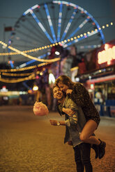 Young couple having fun at a funfair, eating candyfloss - LHPF00117