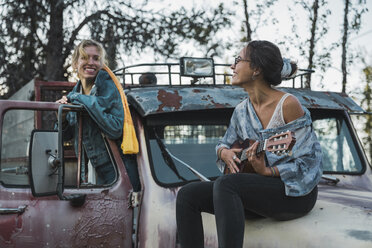 Two friends sitting on a broken truck, playing the ukulele - KKAF02196