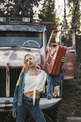 Junge Frau posiert an einem kaputten Oldtimer-Lkw und hält einen Benzinkanister - KKAF02201