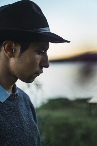 Porträt eines jungen Mannes mit Hut an einem See, lizenzfreies Stockfoto