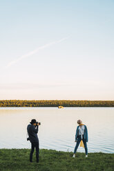 Young man taking pictures of young woman at a alake - KKAF02229