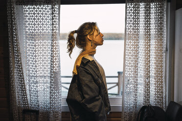 Portrait of a young woman standing in a room with a window - KKAF02232