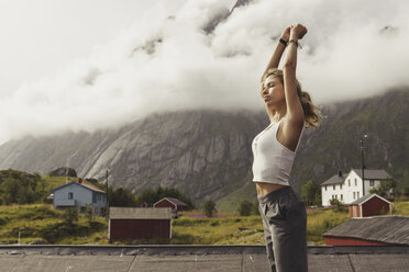Junge Frau steht in der Natur, streckt sich, Lappland, Norwegen - KKAF02237