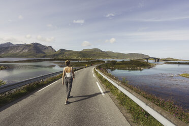 Junge Frau geht auf einer leeren Straße, Lappland, Norwegen - KKAF02240