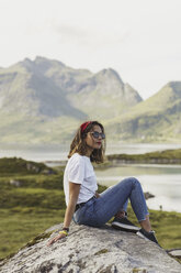 Young woman sitting on a rock, looking at view. Lapland, Norway - KKAF02249