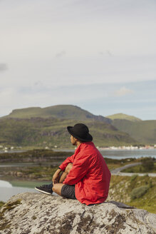 Junger Mann sitzt auf einem Felsen auf der Insel Vesteralen, Lappland, Norwegen - KKAF02251