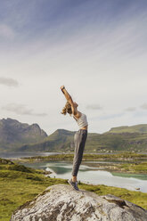 Young woman standing in nature, stretching, Lapland, Norway - KKAF02252