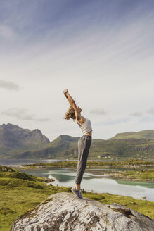 Junge Frau steht in der Natur, streckt sich, Lappland, Norwegen - KKAF02252