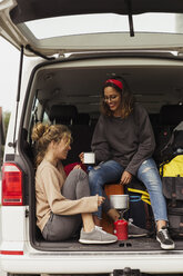 Friends sitting in a camper, taking a break, drinking coffee - KKAF02261