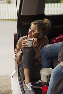 Freunde sitzen in einem Wohnmobil, machen eine Pause und trinken Kaffee - KKAF02262