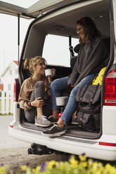 Friends sitting in a camper, taking a break, drinking coffee - KKAF02263