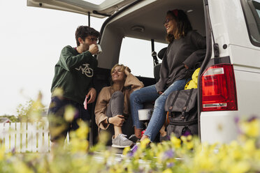 Freunde sitzen in einem Wohnmobil, machen eine Pause und trinken Kaffee - KKAF02264