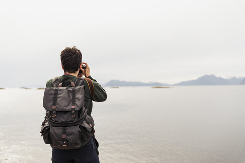 Junger Mann beim Fotografieren eines Sees auf der Insel Vesteralen, Lappland, Norwegen - KKAF02265