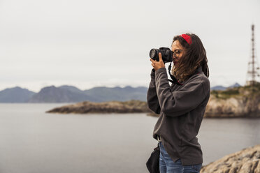 Junge Frau beim Fotografieren eines Sees auf der Insel Vesteralen, Lappland, Norwegen - KKAF02266