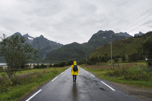 Norwegen, Lappland, Vesteralen-Inseln, Junger Mann geht auf leerer Straße, Rückansicht - KKAF02272