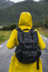 Norwegen, Lappland, Vesteralen-Inseln, Junger Mann geht auf leerer Straße, Rückansicht - KKAF02273