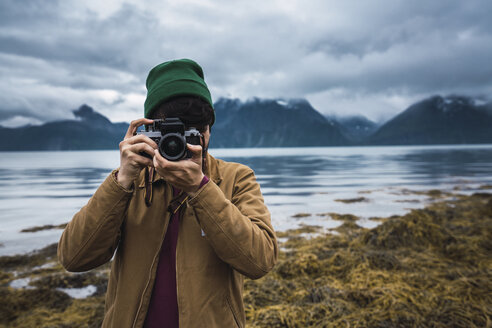 Young man with woolly hat taking pictures with camera - KKAF02292