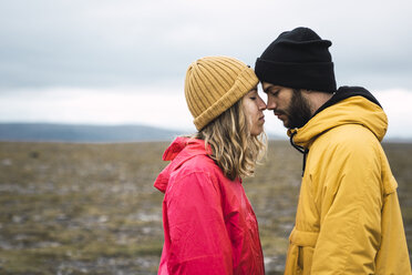 Young couple rubbing affectionately noses, Lapland, Norway - KKAF02300