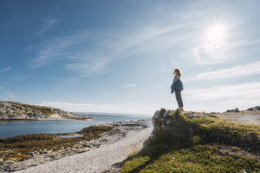 Finland, Lapland, woman standing at the coast in backlight - KKAF02315