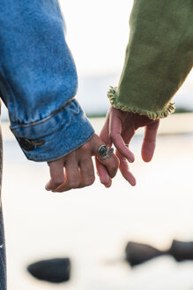 Finland, Lapland, close-up of two young women hand in hand at the lakeside - KKAF02325
