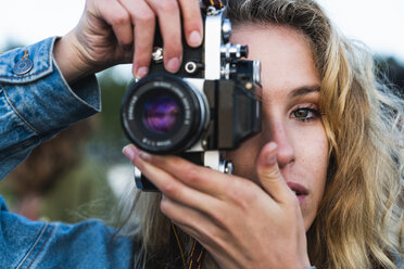 Close-up of beautiful blond young woman taking a picture with a camera - KKAF02336